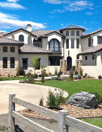 A luxurious two-story house with a landscaped front yard and a curved driveway.