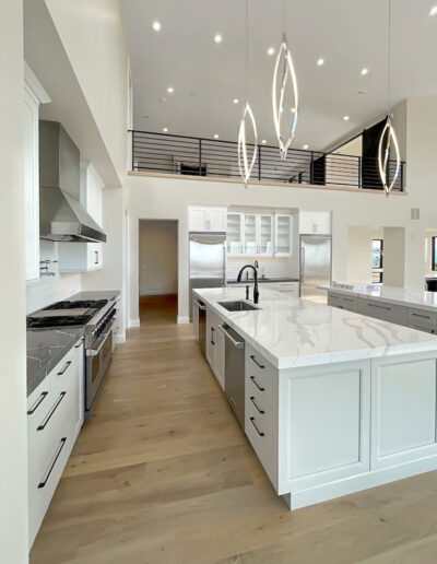 Modern kitchen with white cabinetry, high ceilings, and elegant pendant lighting.