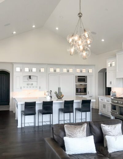 Modern, spacious kitchen with white cabinetry, dark wood floors, and a central island with bar stools.
