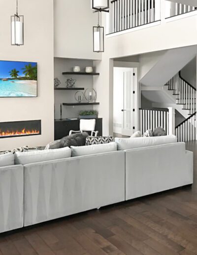 Modern living room with a white sectional sofa, hardwood floors, a wall-mounted fireplace, and a staircase in the background.
