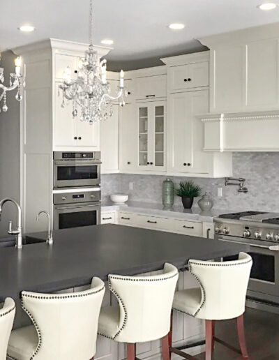 A modern kitchen with white cabinetry, stainless steel appliances, and a central island with seating.