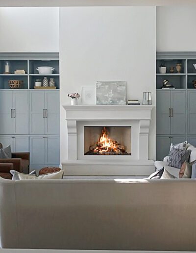 A neatly organized living room with a lit fireplace, built-in shelves, and comfortable seating.