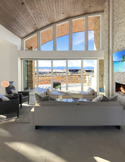 Modern living room with high ceilings, large windows, and a view of the landscape.