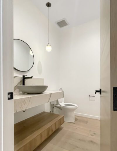 Modern bathroom interior with floating vanity and round mirror.