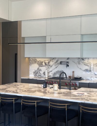 Modern kitchen interior with marble countertops and wooden cabinets.