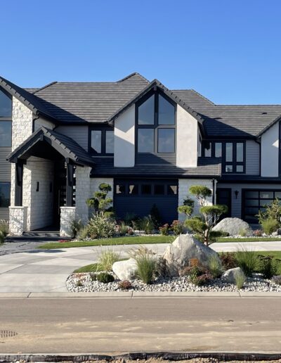 Modern two-story house with a dark gray exterior, white trim, and landscaped front yard.