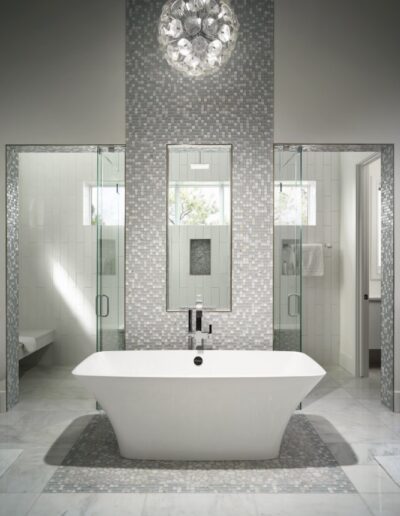 Modern bathroom with a freestanding bathtub, mosaic wall tiles, and a chandelier.