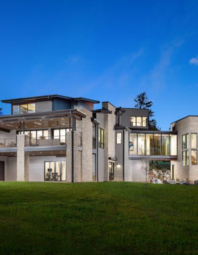 Modern luxury home exterior at twilight with illuminated windows.