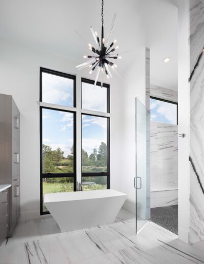 Modern bathroom featuring a freestanding tub, glass-enclosed shower, and floor-to-ceiling windows.