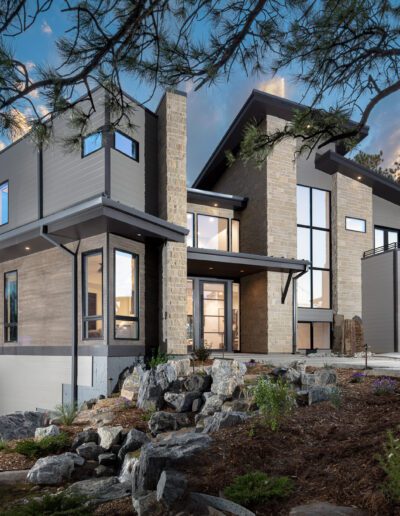 Modern two-story house with large windows and a three-car garage at dusk.