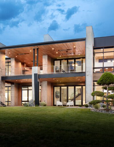 Modern two-story house with large windows and outdoor lighting at dusk.