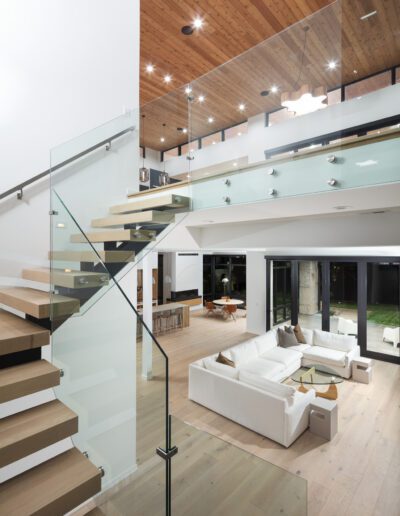 Modern open-plan interior with wooden elements and glass staircase.