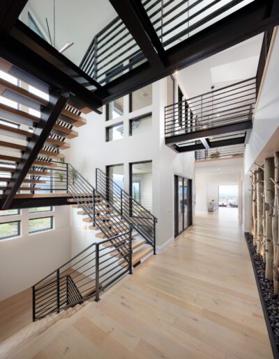 Modern interior showcasing a multi-level staircase with wood steps, black railings, and a spacious, airy design.