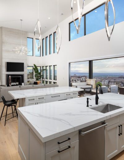 Modern kitchen interior with marble countertops and pendant lighting, featuring a view of the skyline through large windows.