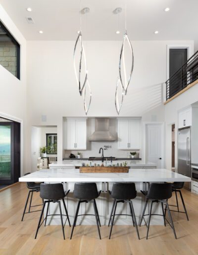 Modern kitchen interior with a large island, bar stools, and an open-plan dining area.