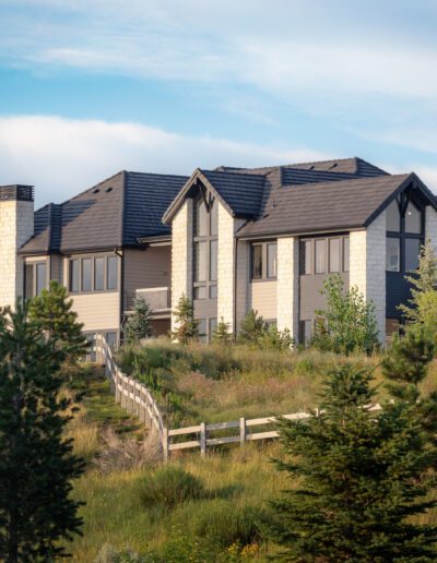 Suburban house nestled on a hillside with a stairway leading up, surrounded by greenery under a cloudy sky.